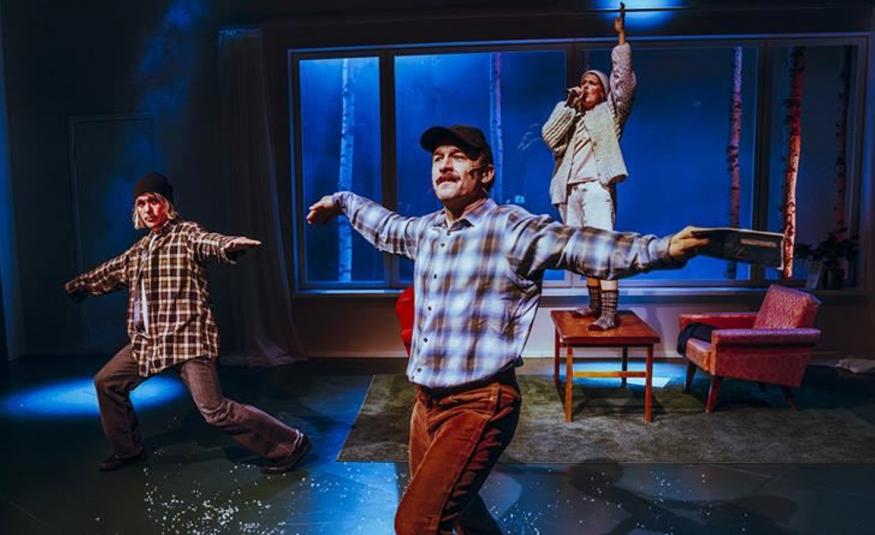 Kuvassa on vasemmalla nuori mies ruutupaidassa tanssiasennossa kädet levitettyinä sivulle ja polvet taivutettuina. Hänellä on ruskea-valkoinen ruutupaita päällään. Keskellä edessä on mies vaalean ruskearuutuisessa paidassa. Taustalla on nuori mies seisomassa tuolin päällä vaaleissa vaatteissa. Taustalla on ikkuna ja kuvan sävy on tumman sininen.