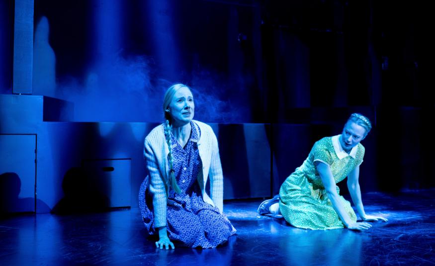 Kuvassa ovat Inka Reyes ja Heidi Ajanto polvillaan näyttämöllä. Kuvan sävy on sininen.