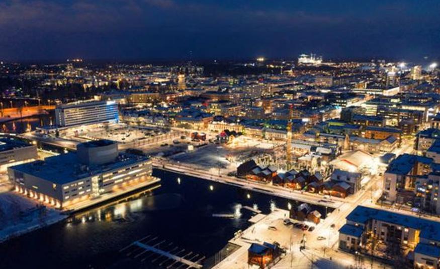 Kuvassa on ylhäältä päin kuvattuna Oulun keskustaa illalla ja se on valaistu. 