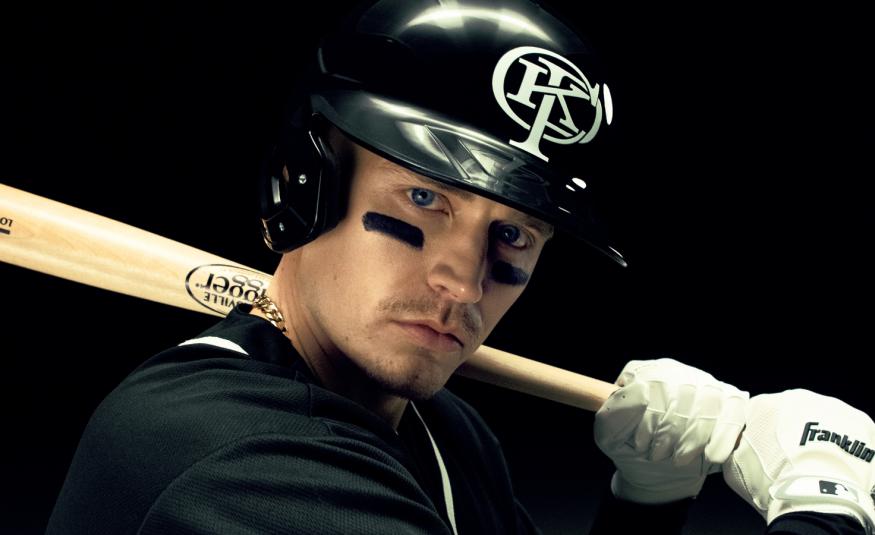 Kuvassa on puolivartalokuvassa Gettomasa mustassa kypärässä ja hän pitää olkapäällään vaaleaa pesäpallomailaa. Hänellä on musta pusero päällään ja tausta on musta.