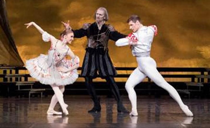 Kuvassa on vasemmalla on valkoisessa kukallisessa rimpsullisessa balettipuvussa kumartuneena. Keskellä on tummapukuinen mies ja oikealla vaaleassa balettipuvussa mies oikea jalka ojentuneena taaksepäin.