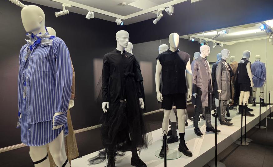 Kuvassa on miesmallinukkeja ja vasemmalla on sinipaitainen mallinukke.  Muut ovat rivissä mustissa ja ruskehtavissa väreissä. 