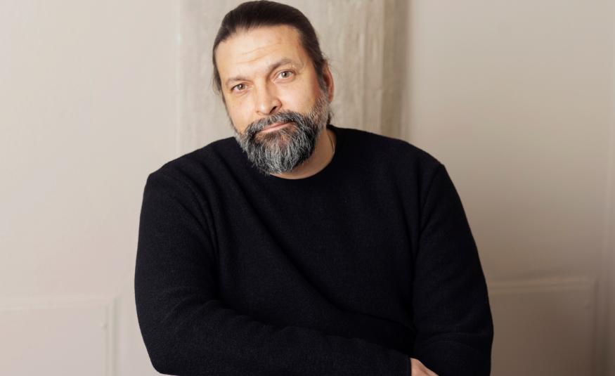 Kuvassa on Riku Saatsi puolivartalokuvassa ja hänellä on musta paita päällään. Tausta on harmahtava.