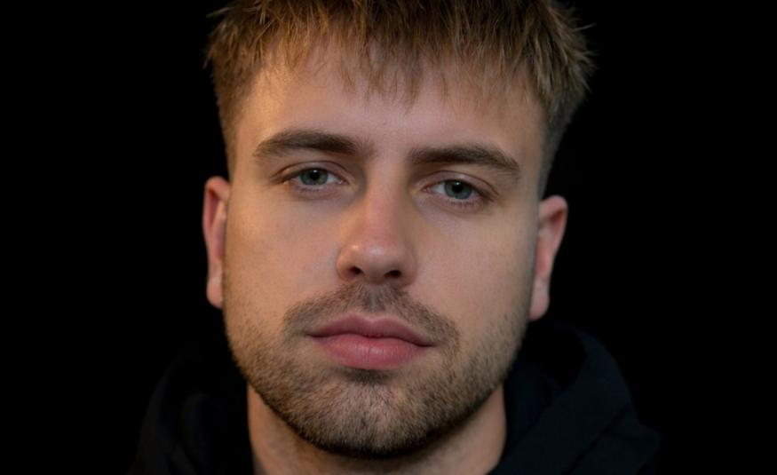 Kuvassa on Rabbe kasvokuvassa. Kuvan sävy on tumma ja tausta tumma.