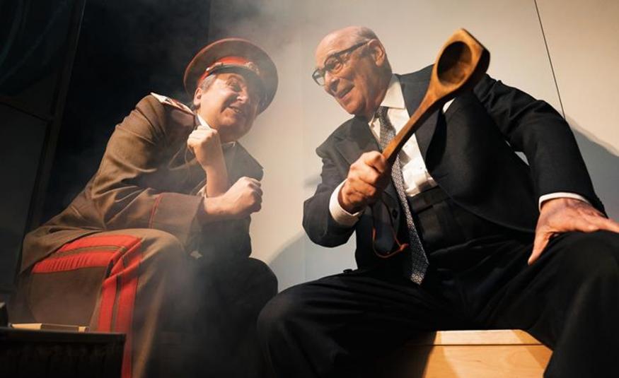 Kuvassa on vasemmalla venäläisessä vihreässä sotilaspuvussa ja -lakissa oleva mies ja oikealla tummassa puvussa Vesa Vierikko kauha oikeassa kädessään. He keskustelevat innokkaasti ja ovat nojautuneina toisiaan kohti.