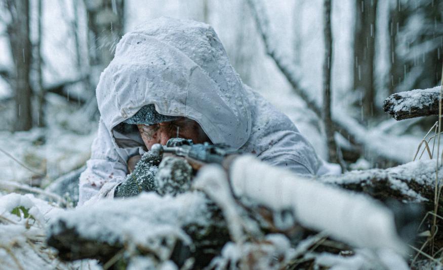Kuvassa on Jarkko Lahti lumihangessa tähtäämässä eteenpäin ja kuva on lähikuva edestä päin. Taustalla on lumista metsää.  