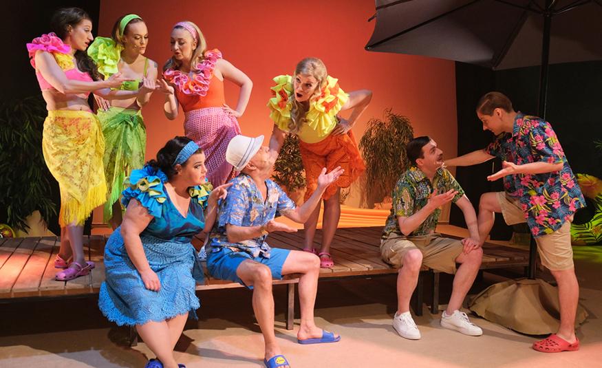 Kuvassa on hieman ylempänä olevalla terassilla seisoo neljä naista ja heillä pastillin värisiä rantamekkoja ja röyhelöt kaulassa. Alempana istuvat sinisessä mekossa nainen ja sinisessä karttapaidassa sekä sinisissä shortseissa mies. Oikealla on kaksi miestä juttelemassa ja heillä on vihertävän sävyiset shortsit ja paidat.