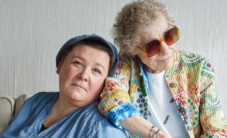 Kuvassa ovat vasemmalla puolivartalokuvassa istumassa vasemmalla Maija Kaunismaa vaalean sinisessä puserossa. Hän nojaa Chrisse Johanssoniin, jolla on aurinkolasit ja turkoosin ja vaalean ruskean kuvioinen pusero päällään. Tausta on vaalea.