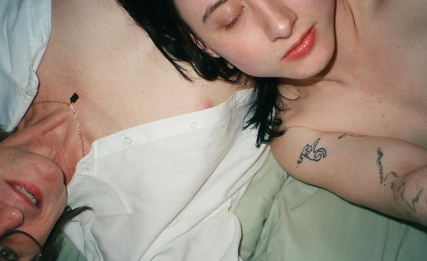 Kuvassa on kaksi naista makaamassa ristikkäin sängyssä ylhäältä päin kuvattuna. Kuvassa näkyy heidän paljasta ylävartaloaan. Oikealla näkyy tummahiuksista naista silmät suljettuina.