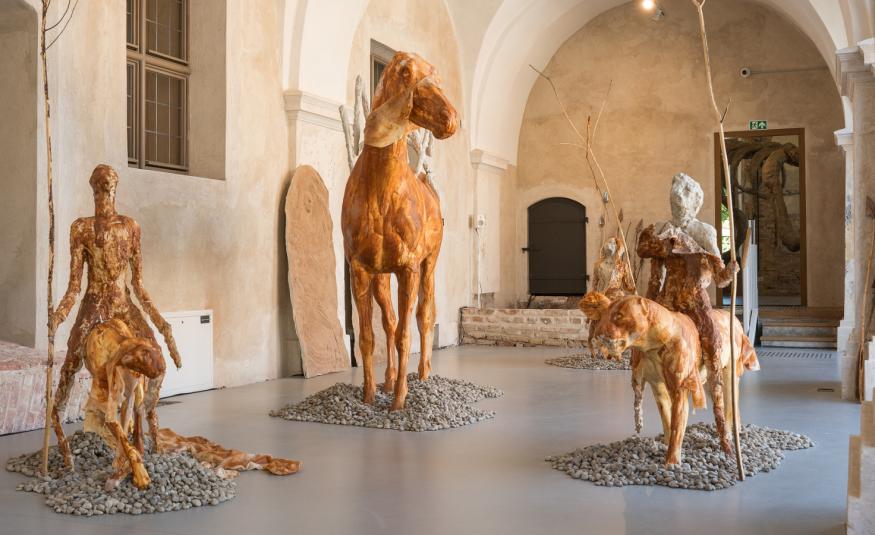 Kuvanveistäjä Edith Karlsonin näyttelyssä kävijä kohtaa nelimetrisiä jättiläisiä, salin ylle kaareutuvan luurangon ja kohti vääjäämätöntä kohtaloaan ratsastavan armeijan. Linnut ja muut eläimet tuijottavat hiljaisina vastaan. Kaivon äärellä lepäilevät merenneidot ovat nousseet vedestä todistamaan, mitä ihminen on merelle ja maalle tehnyt.  Karlsonille tarunomaiset hahmot ovat keino käsitellä kysymyksiä, joita on järkeilemälllä vaikeaa tai mahdotonta ymmärtää. Ihmisiä ja eläimiä yhdistävät vietit, sinnikäs e