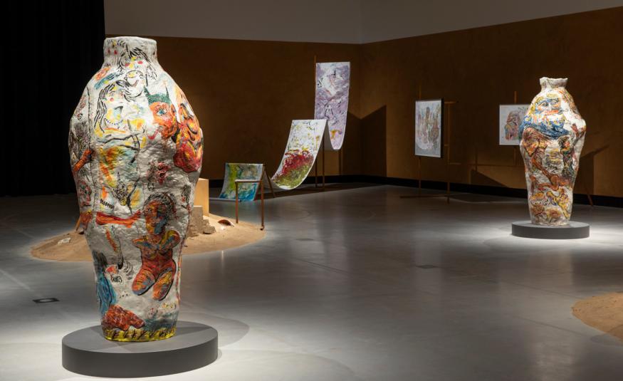 Kuvassa on vasemmalla iso värikäs ruukku ja oikealla taaempana toinen. Takana on liukumäkimäinen ja kaksi jyrkkää ylämäkeä.