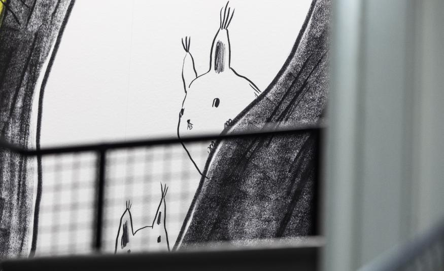 Kuvassa on graafinen teos, joss valkoisella pohjalla kurkkii jänis tumman harmaan verhon takaa. Takaa näkyy ruutuverhoa.