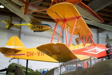 Kuvassa on edessä iso kelta-punainen puinen lentokone ja siinä on rungossa teksti OH-VII punaisella. Taustalla on puenempi kelta-sininen lentokone.
