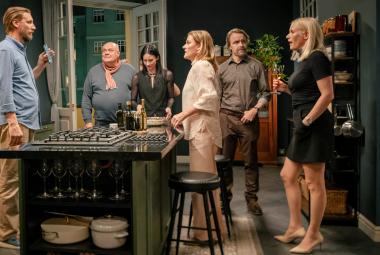 Kuvassa ovat vasemmalta Pekka Streng vaalean sinisessä paidassa, Hannu-Pekka Björkman, Malla Malmivaara, Pirjo Lonka, Jani Volanen ja Laura Birn. Keskellä on pöytä, jonka ympärillä kaikki seisovat. 