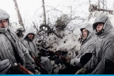 Kuvassa on sotilaita harmaatuneissa lumipuvuissa huput päässään juoksuhaudan laidalla harmaantuneessa lumessa takanaan piikkilankoja. Kuva on osa kirjankannesta.