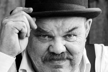 Kuvassa on Jaakko Teppo käavokuvassa ja hänellä on musa lierihattu päässään. Hän pitää oikealla kädellään kiinni hatun lieristä. 