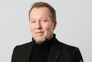 Kuvassa on Mikko Korsulainen kasvokuvassa. Hänellä on musta korkeakauluksinen paika päällään. 