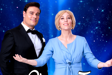 Kuvassa on vasemmalla Tommi soidinmäki tummassa puvussa ja valkoisessa paidassa. Hänen vieressään on Elisa Lairikko vaalean sinisessä mekossa kädet ojennettuina sivulla. Kuva on puolivartalokuva. Tausta on tumman sininen vasemmalla ja muuttuu vaalean siniseksi. Siinä on tähtiä.