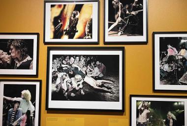 Kuvassa on kellertävällä seinällä musta-valkoisia kuvia. Keskellä olevan ympärillä on kuusi pienempää kuvaa.