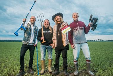 Kuvassa ovat Duudsonien neljä miestä ja heillä on erilaisia työvälineitä kädessään kuten talikko ja golfmaila. Heillä on eri värisiä farkkuja ja puseroita päällään. Taustalla on sini-valkoista taivasta ja alla vihreää heinäpeltoa.