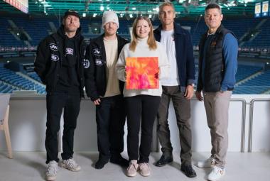 Kuvassa ovat vasemmalta VilleGalle, Jare ja Sari Aalto-Setälä kädessään oranssin pinkki levyn kansi ja Jokereiden edustajat seisomassa Jäähallissa taustallaan tyhjä katsomo.