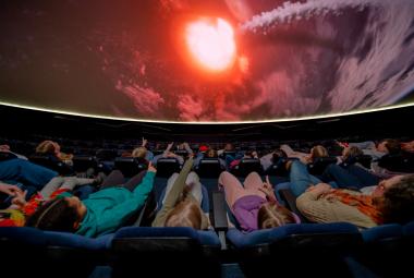 Kuvassa on planetorion lattialla ihmisiä makaamassa pimeässä tilassa ja yläpuolella näkyy punertavaa valoa.