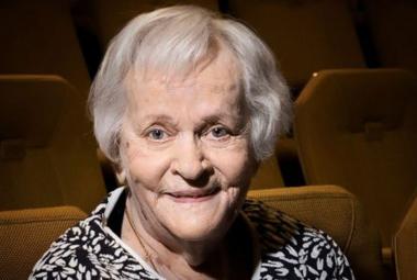 Kuvassa on Eila Roineen kasvokuva ja hänellä on vaalentuneet hiukset. Kuvassa näkyy musta-valkoisen puseron kaula-aukkoa. Taustalla on ruskeita teatterikatsoman tuoleja.