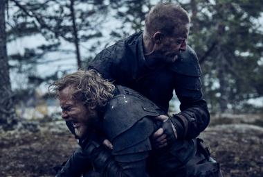 Kuvassa ovat Elias Salonen edessä ja häntä pitää syliotteessa Eero Aho. Taustalla on mäntymetsää.