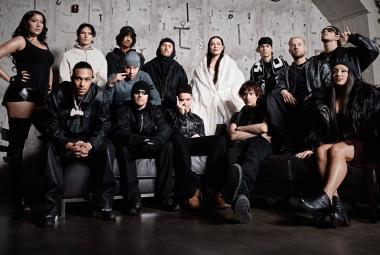 Kuvassa on kahdessa rivissä artistit ja takana on kahdeksen mies ja naisartistia, edessä viisi istumassa. Heillä on mustat vaatteet paitsi kadella valkoiset.