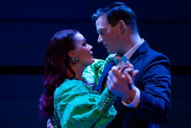 Kuvassa ovat Ella Mustajärvi vaalean vihreässä puhvihihaisessa mekossa ja Juho Markkanen tumman sinisessä takissa puolivartalokuvassa. He ovat vastakkain tanssiasennossa. Tausta on tumma.