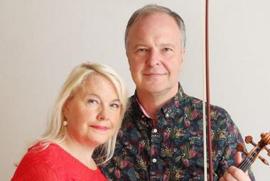 Kuvassa ovat puolivartalokuvassa Anu Komsi punaisessa puserossa ja Sakari Oramo tumman kirjavassa paidassa. Tausta on vaalea.