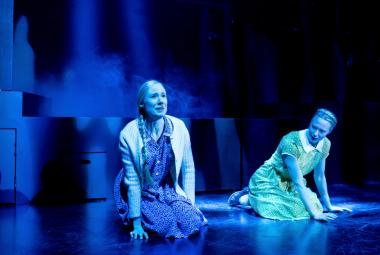 Kuvassa ovat Inka Reyes ja Heidi Ajanto polvillaan näyttämöllä. Kuvan sävy on sininen.