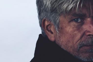 Kuvassa on Karl Ove Knausgård oikeassa laidassa kasvokuvassa.  Hän on hieman vinottain ja kasvojen sävy on tummahko. tausta on harmaa.