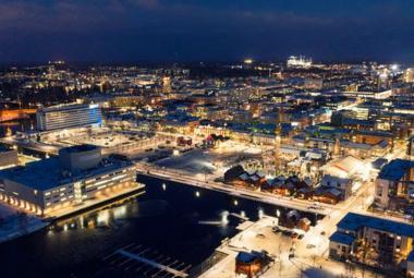 Kuvassa on ylhäältä päin kuvattuna Oulun keskustaa illalla ja se on valaistu. 