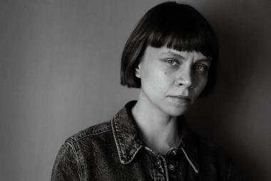 Kuvassa on Mariia Niskavaara ja hän on puolivartalokuvassa. Hänellä on farkkutakki päällään. Tausta on tumma. Kuva on musta-valkoinen.