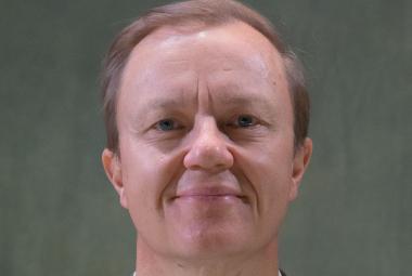 Kuvassa on Mika Nuojua kasvokuvassa. Tausta on harmahtava.