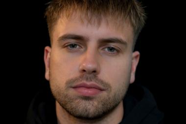 Kuvassa on Rabbe kasvokuvassa. Kuvan sävy on tumma ja tausta tumma.