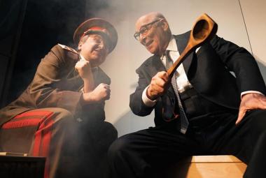 Kuvassa on vasemmalla venäläisessä vihreässä sotilaspuvussa ja -lakissa oleva mies ja oikealla tummassa puvussa Vesa Vierikko kauha oikeassa kädessään. He keskustelevat innokkaasti ja ovat nojautuneina toisiaan kohti.