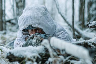 Kuvassa on Jarkko Lahti lumihangessa tähtäämässä eteenpäin ja kuva on lähikuva edestä päin. Taustalla on lumista metsää.  