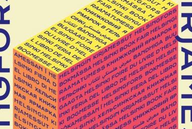 Kuvassa on kuutiomainen piirros ja siinä on päällä keltaista, sivussa oranssia ja edessä punaista pintaa. Kaikissa on isoin kirjaimin eri kielillä Helsingin Kirjamessut. Molemmissa on pystyssä isolla sama teksti isoin tumman sinisin kirjaimin. Tausta on vaalean keltainen.