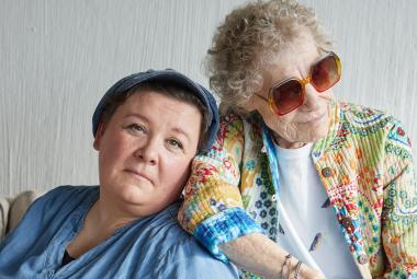 Kuvassa ovat vasemmalla puolivartalokuvassa istumassa vasemmalla Maija Kaunismaa vaalean sinisessä puserossa. Hän nojaa Chrisse Johanssoniin, jolla on aurinkolasit ja turkoosin ja vaalean ruskean kuvioinen pusero päällään. Tausta on vaalea.