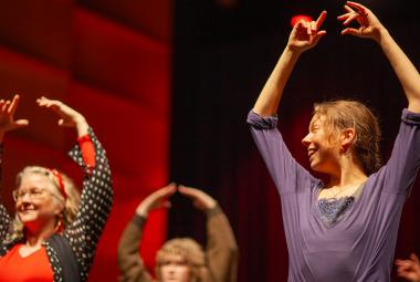 Kuvassa on puolivartalokuvassa kolme flamenco-tanssijaa ja heillä on kädet ylhäällä. Taustalla on punertavaa seinää. 