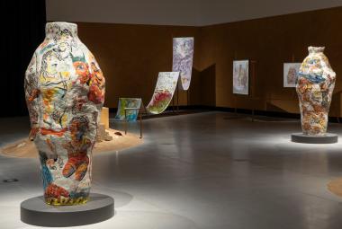 Kuvassa on vasemmalla iso värikäs ruukku ja oikealla taaempana toinen. Takana on liukumäkimäinen ja kaksi jyrkkää ylämäkeä.