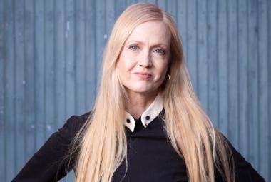 Kuvassa on Eveliina Talvitie puolivartalokuvassa ja hänellä on musta pusero päällään. Hänellä on pitkät vaaleat hiukset. Tausta on sininen. 