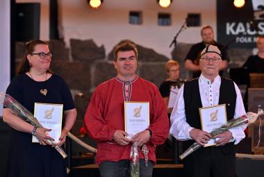 Kuvassa ovat vasemmalta Riina Sakala mustassa mekossa. Keskellä on Jaakko Kyrö punaisessa puserossa ja oikealla Alpo Suonvieri mustassa liivissä ja valkoisessa paidassa. Kaikilla on kurnniakirjat ja ruusut kädessään. 