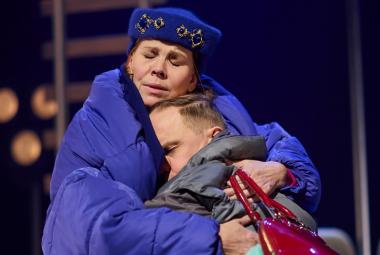 Kuvassa on Eeva Soivio isossa sinisessä toppatakissa ja hän pitää sylissään halauksessa Jarkko Lahtea. 